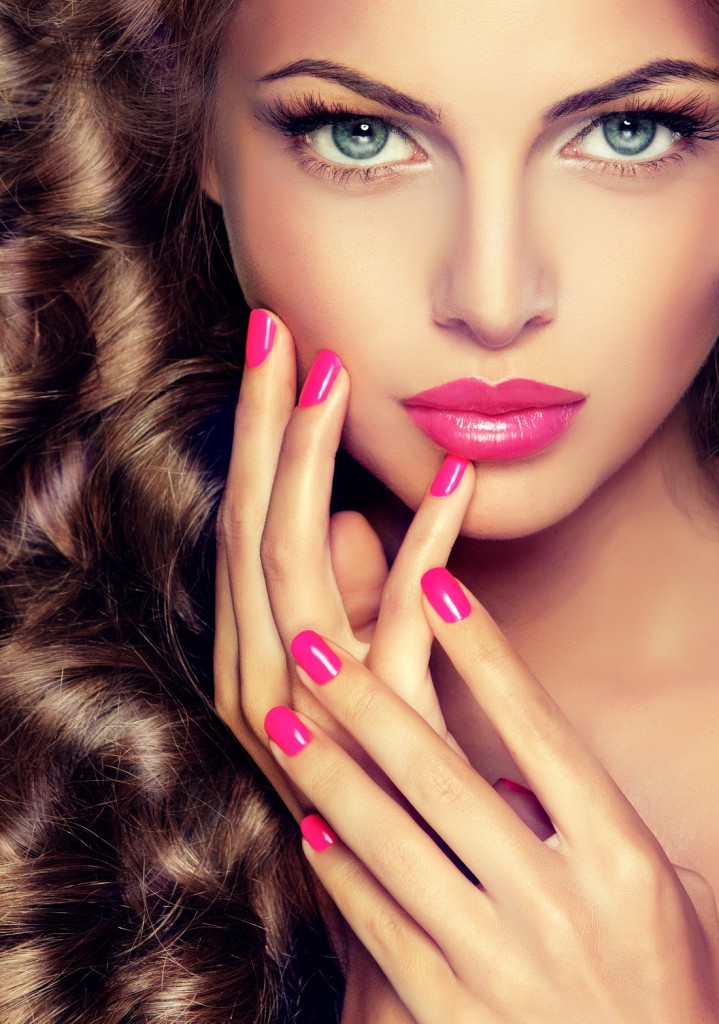 Beautiful model brunette with long curled hair . Hairstyle wavy curls . Crimson nails  manicure .Makeup   color fuchsia .